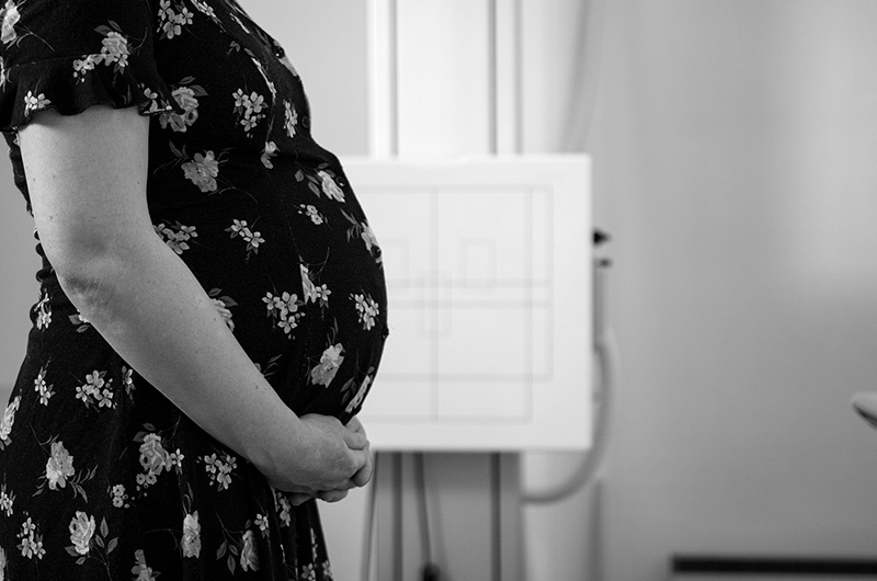 A pregnant woman in a dress holding her stomach